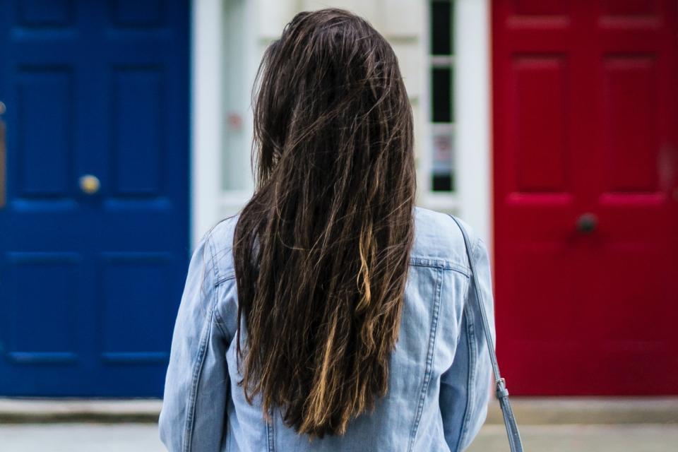 A woman choosing between a blue door and a red door